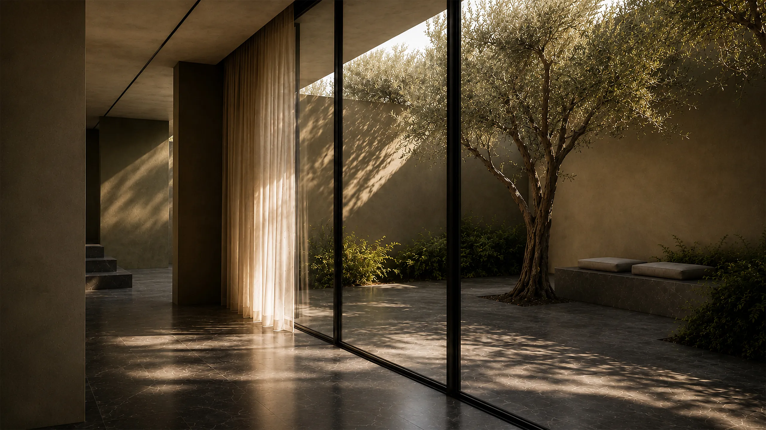Luxury interior opening toward a private courtyard with an olive tree, deep shade, filtered sunlight and a protected relationship between inside and outside.