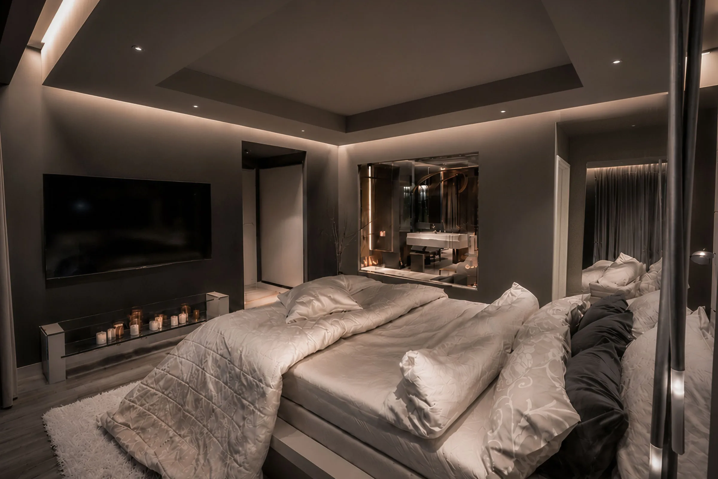 Warm modern bedroom in a Tehran family apartment with layered neutral textiles, dark wall panels and integrated ceiling lighting.
